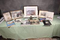 Wide shot of all Philadelphia-related items on a green cloth-covered table, showing framed prints, bottles, books, and souvenirs arranged for display.
