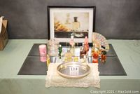 Overview photo of the lot showing mirror tiles, perfume bottles, silver tray on lace doily, and framed print in background