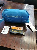 Blue Halti Summerlite L sleeping bag in compression sack with Ruko cutting tool and blades on table