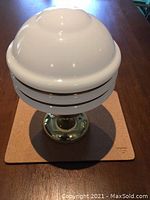 Photo showing the white glass ribbed globe with brass mounting base from the top view.