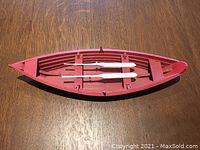 Top-down view showing the interior red paint and white oars of the wooden dory boat model.