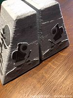Pair of trapezoidal carved soapstone bookends with Inuit figures shown from the side.