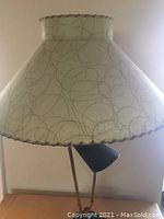 Front view of tri-light lamp unlit, showing green parchment large shade with squiggly abstract pattern and scalloped burgundy edging. Smaller directional spotlight visible below shade.