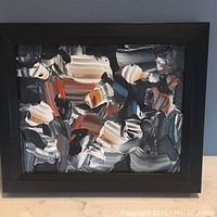 Front view of framed abstract impasto painting showing black, white, gray, orange brush strokes.