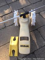 Photo of the Nelson RainTrain Traveling Lawn Sprinkler showing the front with yellow body, large white spiked wheels, and metal arm for water distribution.