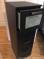 Ikea BRIMNES 4-drawer chest with top drawer open showing frosted glass front and metal handle