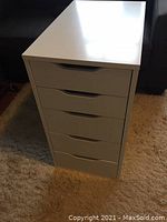 Front view of white Ikea ALEX unit showing all five drawers closed and unit shape.