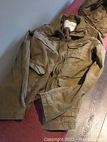 Khaki beige bomber jacket laid flat, showing front with multiple flap pockets and collar.