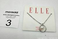 Front view of ELLE branded display card with sterling silver necklace featuring a white pearl pendant in circular frame.