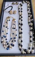 Full view of the lot showing two necklaces and two pairs of clip-on earrings arranged in a tray