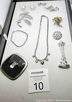 Overview of various rhinestone jewelry pieces on white background including brooches, earrings, a necklace and a bracelet.