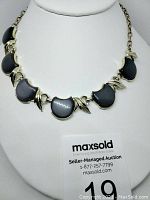 Vintage Charcoal Lucite Moonglow choker necklace displayed on white padded jewelry stand, showing front detail with crescent inserts and metal leaf accents.