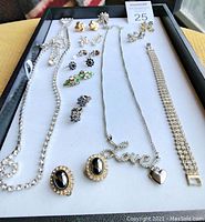 Full view of rhinestone jewelry laid out on a white tray including necklaces, earrings, and bracelet.