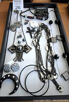 Top view showing assorted jewelry including necklaces, bracelets, earrings on white background in black frame tray