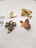 Four vintage brooches arranged on a white background showing all brooch styles