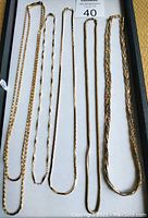 Six gold tone chain necklaces displayed on a white tray with a MaxSold auction number 40 label. Chains show various link styles and lengths.