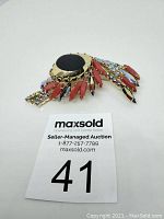 Top front view of the colorful rhinestone brooch showing red, black, and clear stones and gold-tone setting.