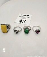 Overview of all four rings on white surface with auction tag