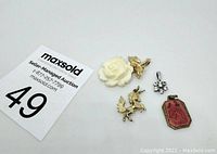 Five assorted pendants arranged on white background alongside auction card.