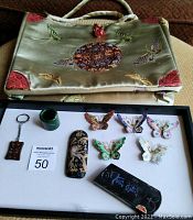 Photo of two Asian purses with embroidered butterfly and medallion designs, and several small ornamental items on a white tray.