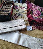 Lot showing two scarves, beaded shawl, purse and satin gloves on a bench.