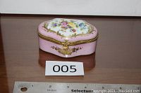 Closed pink Limoges trinket box with floral painted lid and gold accents shown with ruler for size reference.