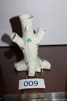 Front view of Belleek tree trunk porcelin bud vase showing 3 openings and shamrock design