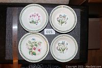 Top view of 3 cereal bowls and 1 bread & butter plate showing floral botanical designs with green leaf borders.