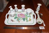 Complete assortment of Portmeirion botanical tableware and serveware on a wooden table along with metal ruler for scale and lot tag 016.
