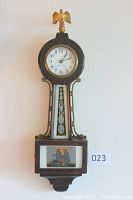 Full front view of mahogany banjo clock hung on wall, showing overall design and proportions.