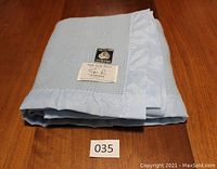 Folded baby blue wool blanket showing overall condition and labels.