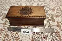 Side view of the rectangular wooden box showing the carved geometric pattern on the lid and the hinged construction.