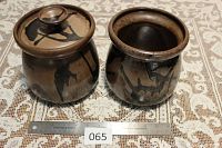Pair of Blue Mountain Pottery mocha bean pots placed side by side on lace tablecloth, one with lid, one open, ruler placed in front for scale showing size about 7.5 inches tall.