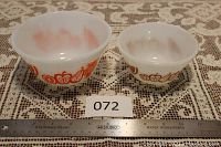 Two Federal Fire-King bowls side by side. Larger bowl with orange pattern and smaller bowl with brown pattern, on lace tablecloth with ruler for scale.