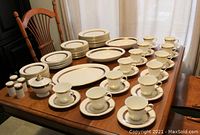 Angled view of full set arranged on table showing plates, cups, bowls, platter and shakers
