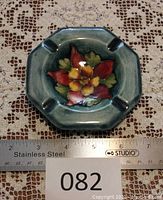 Top view of the octagonal Moorcroft ashtray showing the central floral Columbine design and four cigarette rests, measuring about 4.5 inches wide.