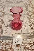 Front and side view of cranberry hand-blown glass vase with diamond optic pattern, showing double handles and ruffled top.