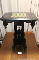 Front view showing gold checkerboard top and carved pedestal base