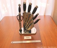 Photo of Carl Weill 8-piece stainless steel cutting utensil set on polished wooden table with ruler for scale.