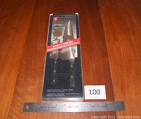 Photo of the unopened Presidents Choice cutting utensil set in original black box on wooden table with ruler for scale.