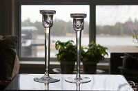 Pair of Waterford crystal candlestick holders shown on a glass table in front of a window, one slightly taller than the other