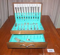 Photo of entire silverplate flatware set neatly arranged in open wood case showing upper section with knives and lower drawer with spoons and forks.