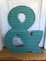 Front view of large teal corrugated metal ampersand sign showing shape and distressed finish.