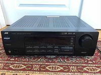 Front view of black JVC audio visual receiver showing control buttons, knobs and display