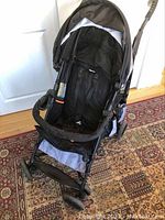Front view of Summer 3D Trek stroller with padded seat, safety harness, and canopy, positioned on patterned rug.