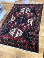 Full view of the rug on wooden floor showing its overall geometric floral design and color scheme.