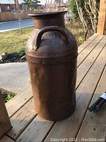 Full view of vintage metal milk jug showcasing cylindrical shape, handles, and surface condition.