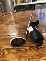 Photo of left-handed Adams Super 5 golf club with protective head cover on wooden table.