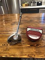 TaylorMade Chaska putter laying on wooden table with TP Collection headcover beside it, showing full putter length and grip.