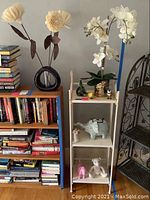 Artificial flowers on shelves with black modern vase and gold planter